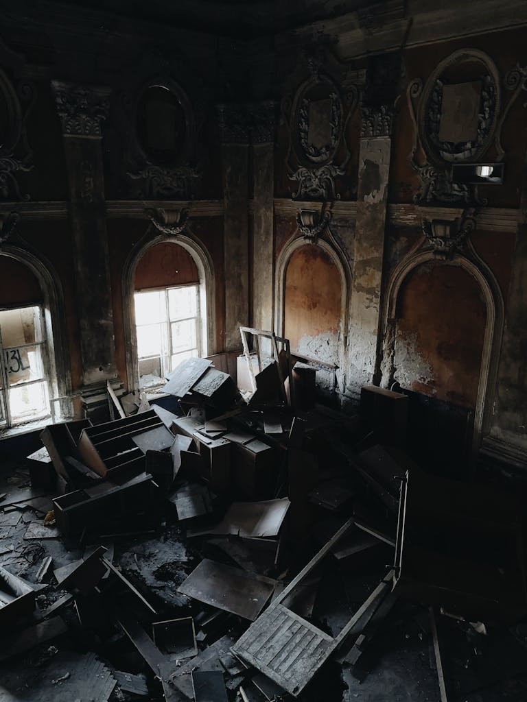 Dark, decaying interior of an abandoned building filled with broken furniture and debris, evoking a creepy atmosphere.